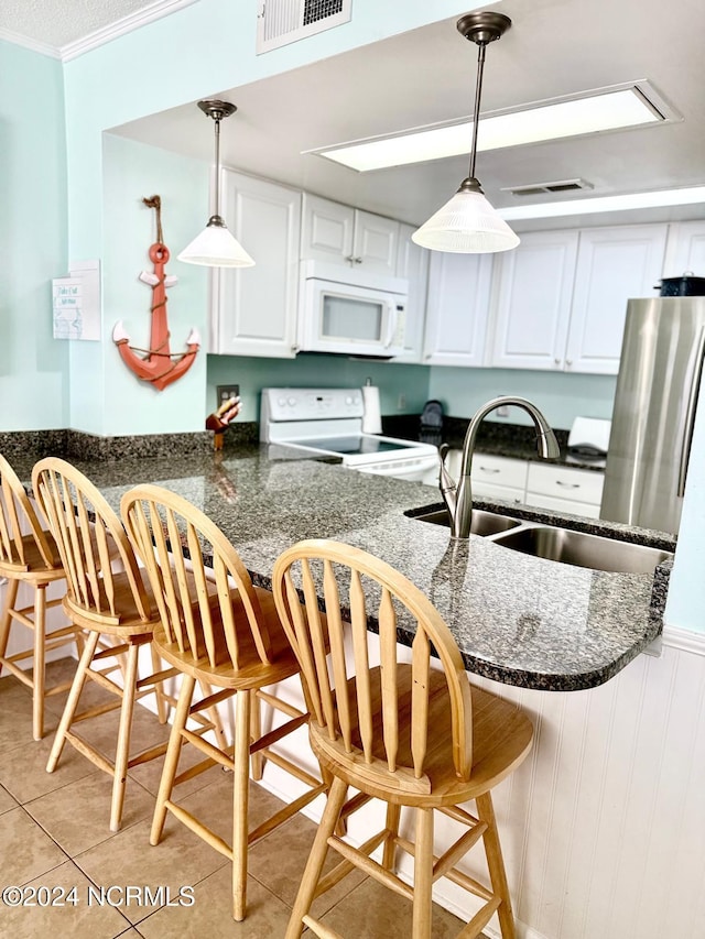 kitchen featuring a kitchen breakfast bar, hanging light fixtures, sink, stove, and white cabinets