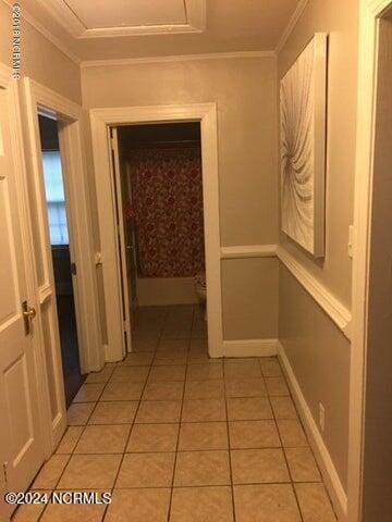 corridor featuring ornamental molding and light tile patterned flooring