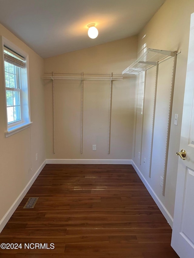 spacious closet with dark wood-type flooring and lofted ceiling