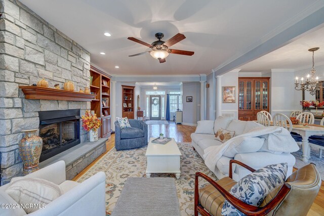 living room with built in features, light hardwood / wood-style flooring, a fireplace, and crown molding