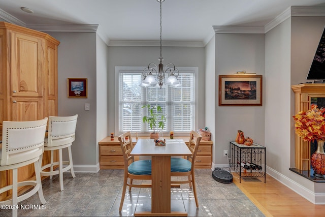 dining space with light hardwood / wood-style floors, ornamental molding, and an inviting chandelier