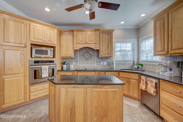 kitchen with a kitchen island, appliances with stainless steel finishes, ornamental molding, dark stone countertops, and sink