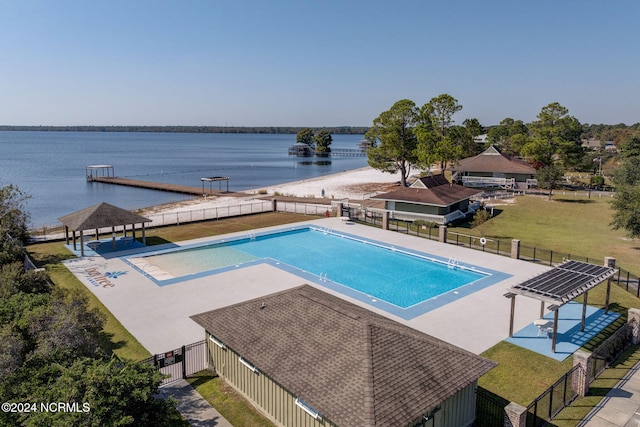 view of pool with a water view, a lawn, and a boat dock