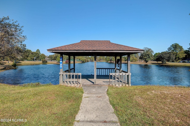 view of dock with a yard and a water view