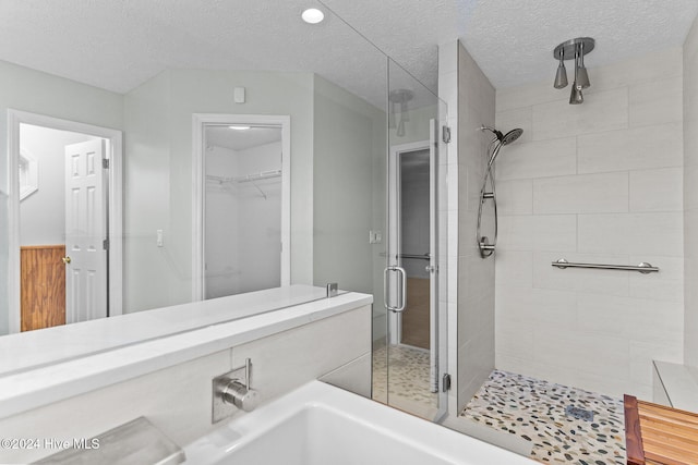 bathroom featuring a textured ceiling and a shower with door