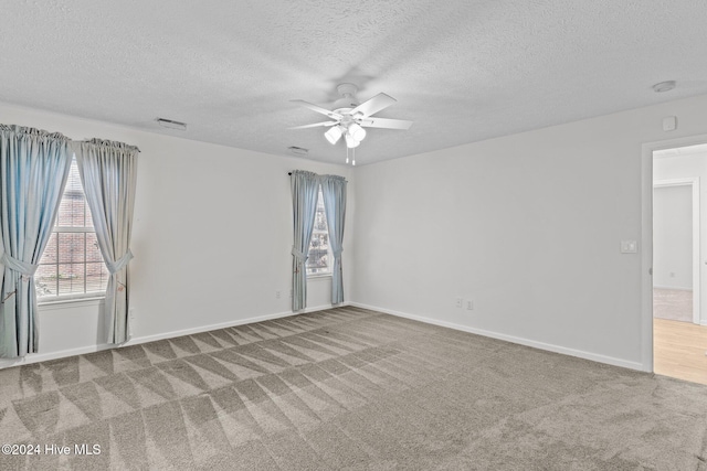 unfurnished room with carpet flooring, ceiling fan, and a textured ceiling