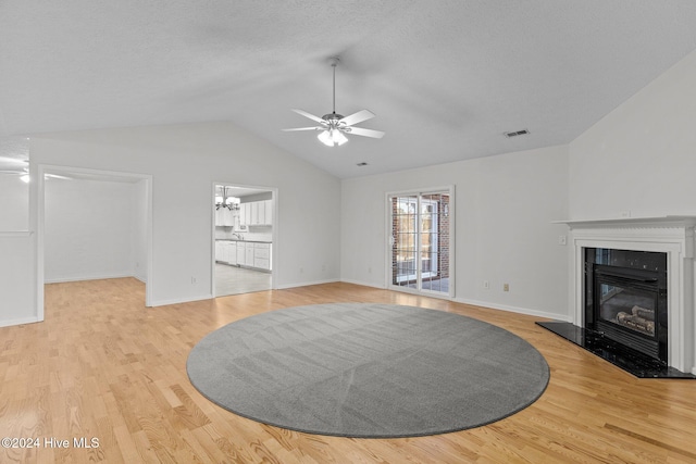 unfurnished living room featuring a textured ceiling, light hardwood / wood-style floors, vaulted ceiling, and ceiling fan