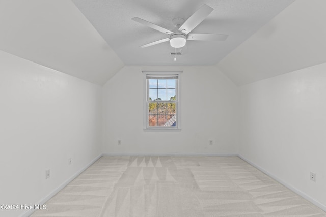 additional living space featuring a textured ceiling, light carpet, ceiling fan, and vaulted ceiling