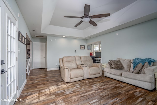 living room featuring ceiling fan, a raised ceiling, and dark hardwood / wood-style flooring