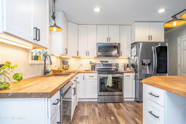 kitchen featuring pendant lighting, butcher block countertops, stainless steel appliances, and white cabinets