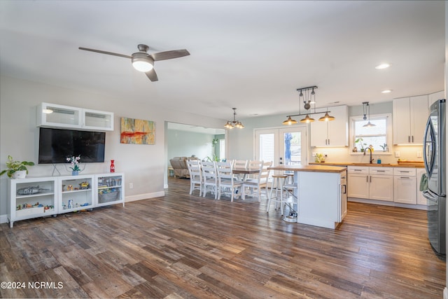 kitchen with a kitchen island, butcher block counters, dark hardwood / wood-style flooring, white cabinetry, and pendant lighting