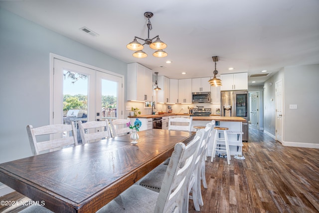 dining space with french doors, an inviting chandelier, and dark hardwood / wood-style floors