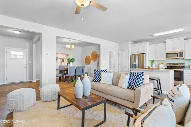 living room with light hardwood / wood-style flooring and ceiling fan with notable chandelier