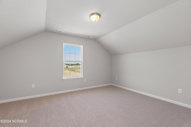 bonus room with vaulted ceiling and carpet flooring