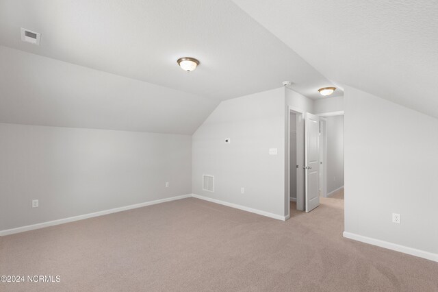 bonus room with light carpet and lofted ceiling