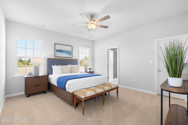 bedroom with light carpet, multiple windows, and ceiling fan