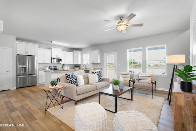 living room with sink, light wood-type flooring, and ceiling fan