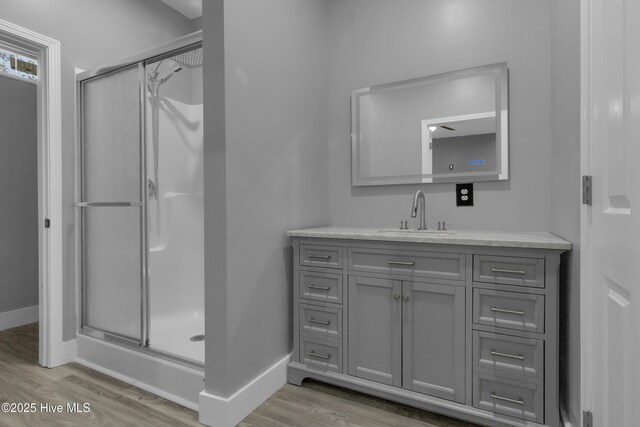 bathroom with hardwood / wood-style flooring, vanity, and an enclosed shower