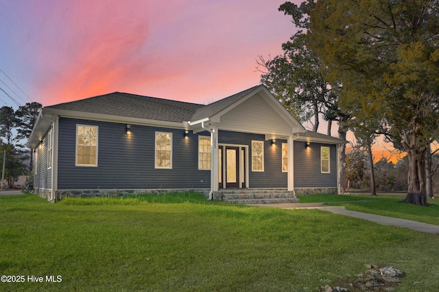 view of front of house with covered porch, a front lawn, a chimney, and a shingled roof