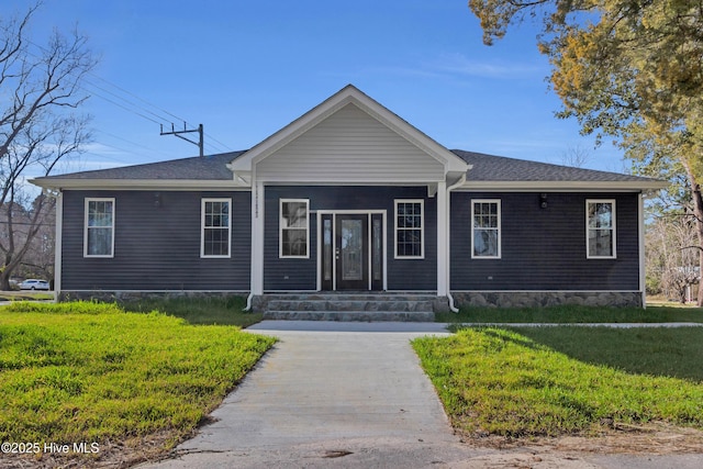 view of front facade with a shingled roof and a front yard