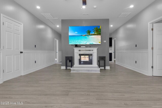 unfurnished living room featuring light wood finished floors, recessed lighting, visible vents, attic access, and a glass covered fireplace