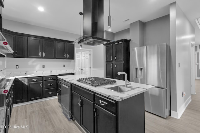 kitchen featuring a center island, island exhaust hood, appliances with stainless steel finishes, a sink, and dark cabinets