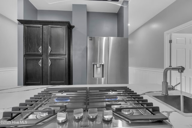 room details with appliances with stainless steel finishes, wainscoting, and a decorative wall