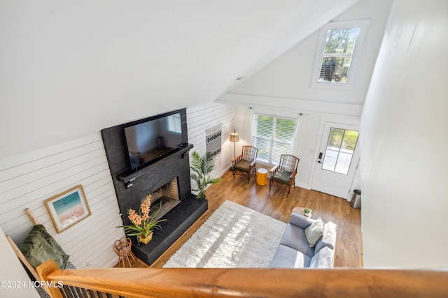 living room featuring light hardwood / wood-style floors, lofted ceiling, and a brick fireplace