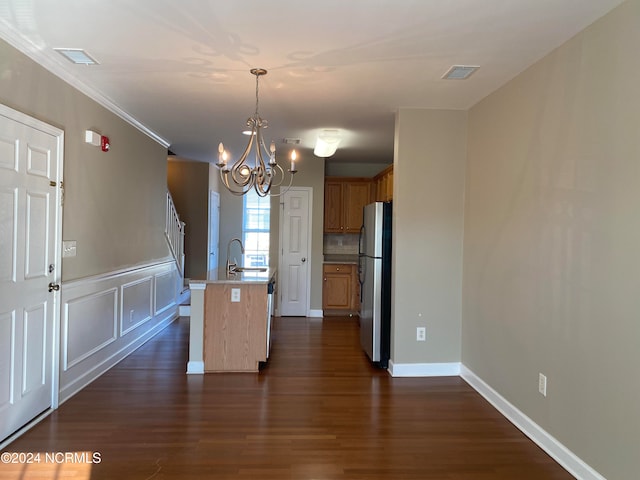 kitchen featuring hanging light fixtures, dark hardwood / wood-style flooring, an island with sink, and stainless steel refrigerator