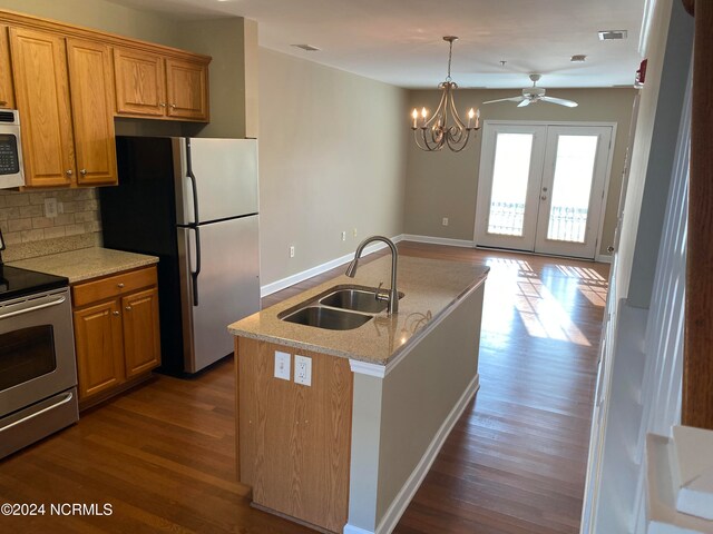 kitchen with sink, stainless steel appliances, tasteful backsplash, dark hardwood / wood-style floors, and a center island with sink