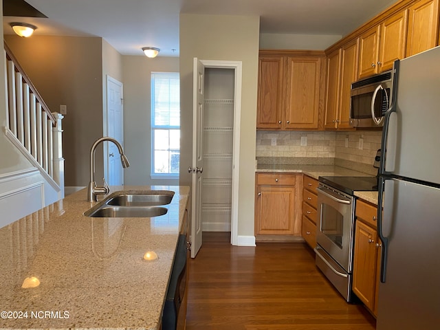 kitchen featuring sink, light stone counters, dark hardwood / wood-style flooring, backsplash, and appliances with stainless steel finishes