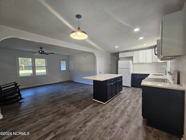 kitchen featuring dark hardwood / wood-style floors, a center island, pendant lighting, white refrigerator, and white cabinetry