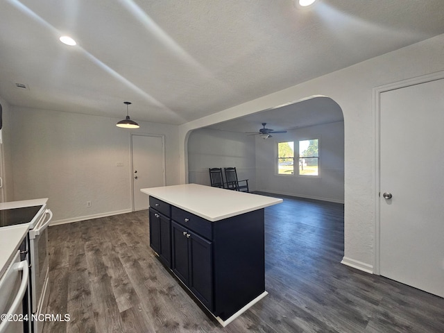 kitchen with hanging light fixtures, ceiling fan, dark hardwood / wood-style floors, stainless steel range with electric stovetop, and a center island