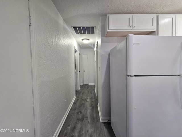 kitchen featuring dark wood-type flooring, white cabinets, a textured ceiling, and white refrigerator