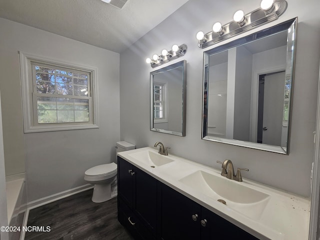 bathroom featuring wood-type flooring, a textured ceiling, a washtub, toilet, and vanity