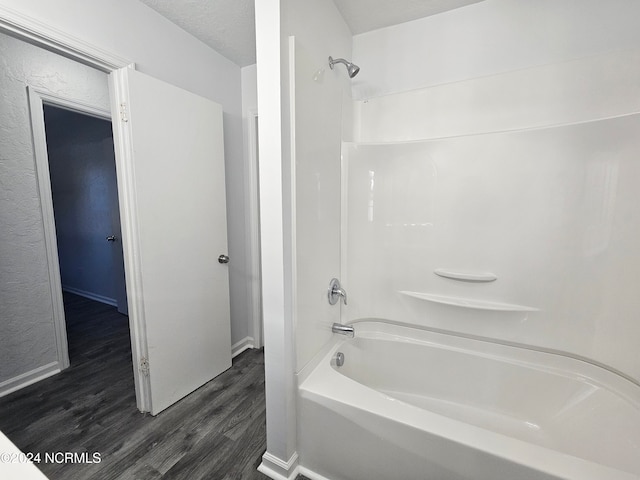 bathroom featuring wood-type flooring, a textured ceiling, and tub / shower combination