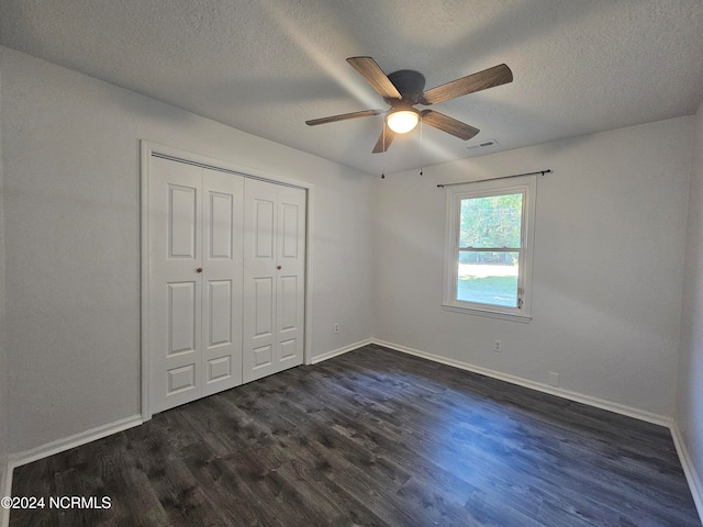 unfurnished bedroom with a textured ceiling, dark wood-type flooring, and ceiling fan