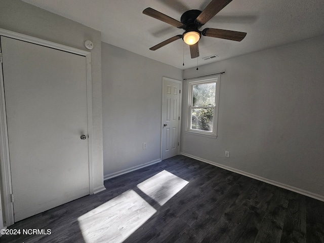 unfurnished bedroom featuring dark hardwood / wood-style flooring, a closet, and ceiling fan