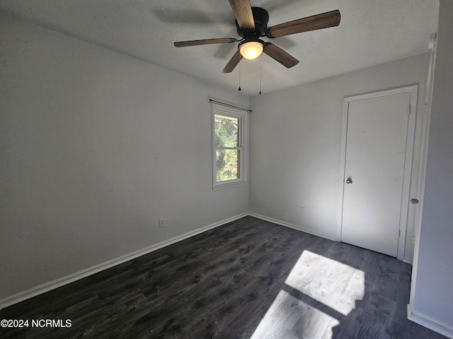 unfurnished bedroom with ceiling fan, a textured ceiling, and dark hardwood / wood-style floors