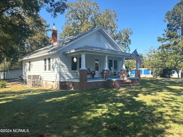 view of front of property featuring a front yard, cooling unit, and covered porch