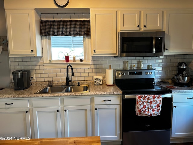 kitchen with tasteful backsplash, appliances with stainless steel finishes, sink, and white cabinets