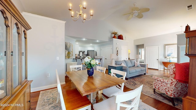 dining space featuring ornamental molding, ceiling fan with notable chandelier, wood-type flooring, and high vaulted ceiling