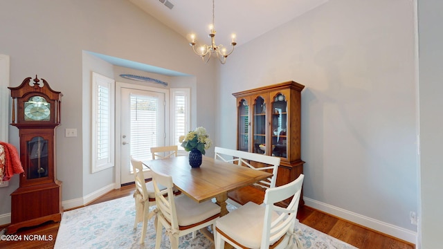 dining room with an inviting chandelier, wood-type flooring, and vaulted ceiling