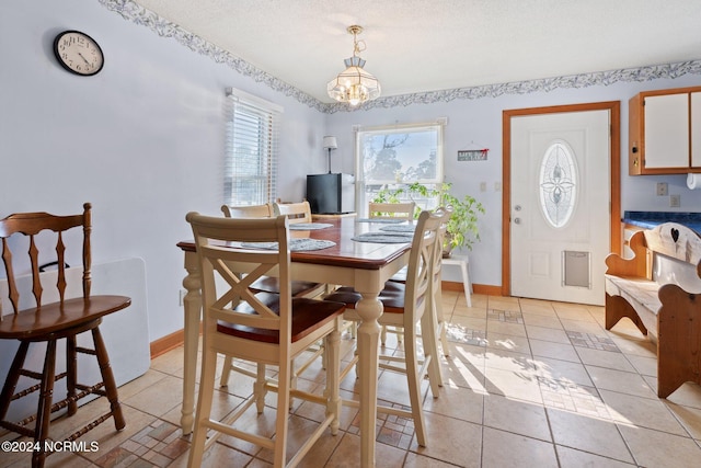 dining area with a chandelier, a textured ceiling, and light tile patterned floors