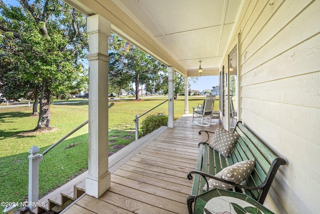 wooden terrace featuring covered porch and a lawn