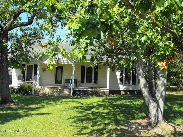 view of property hidden behind natural elements with a front yard and covered porch