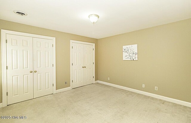 unfurnished room featuring a wealth of natural light, light colored carpet, visible vents, and baseboards