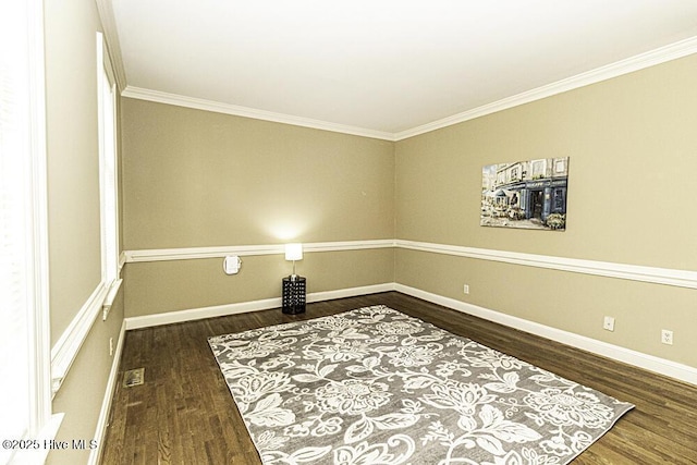 empty room featuring ornamental molding, baseboards, and wood finished floors