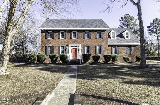 colonial house featuring brick siding and a front lawn