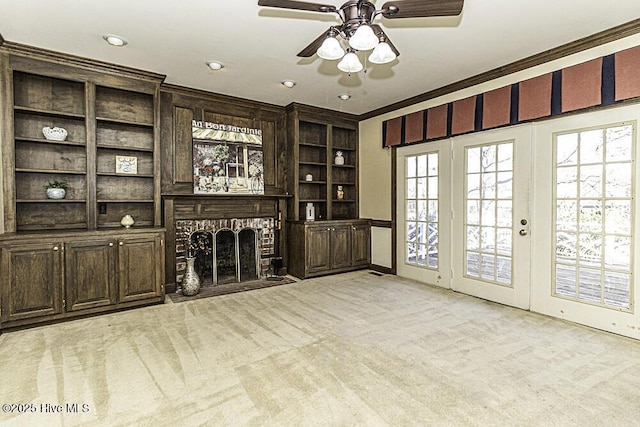 unfurnished living room featuring french doors, light colored carpet, ornamental molding, a ceiling fan, and a brick fireplace